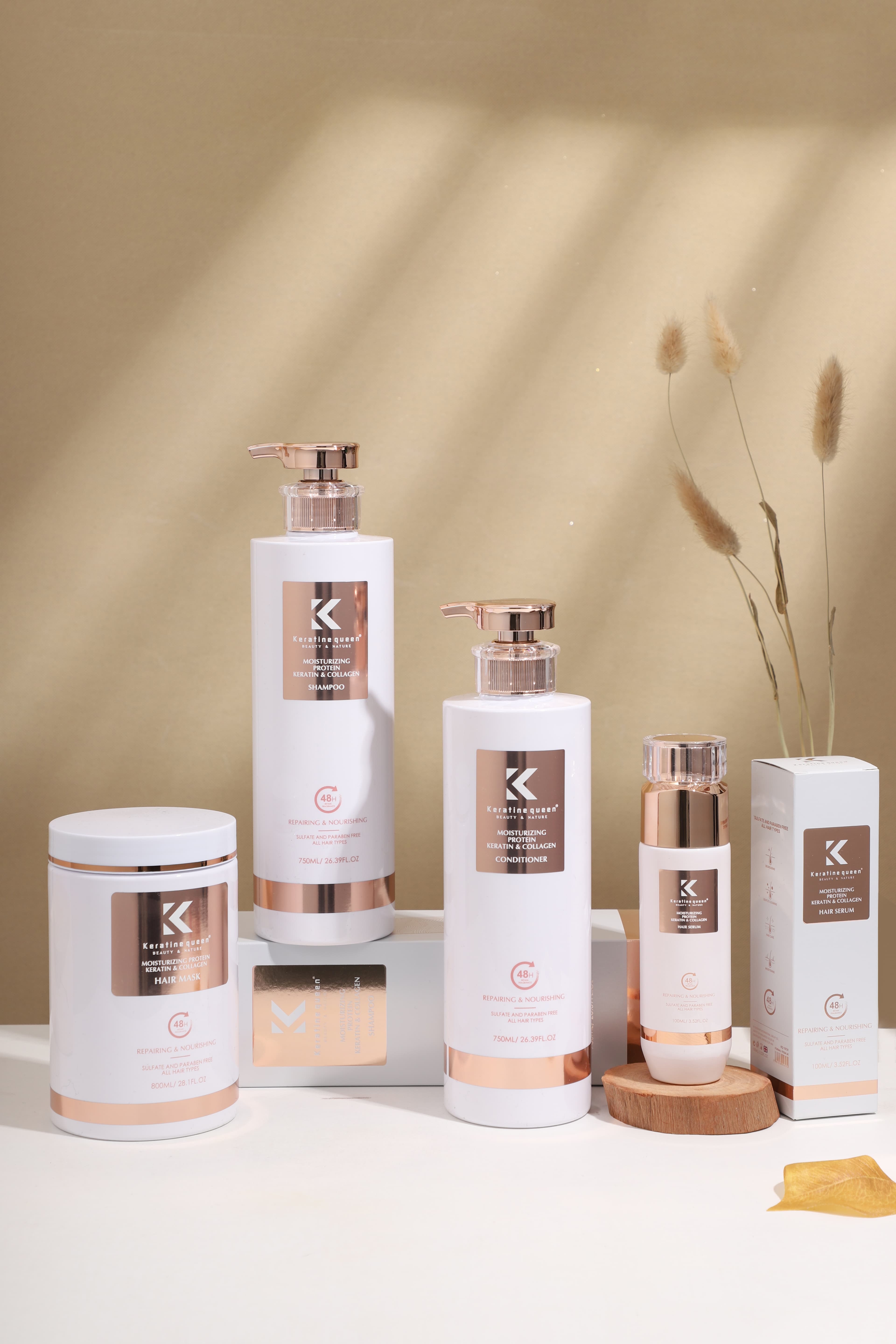 Keratine Queen hair care set in white and rose gold packaging on a warm background.